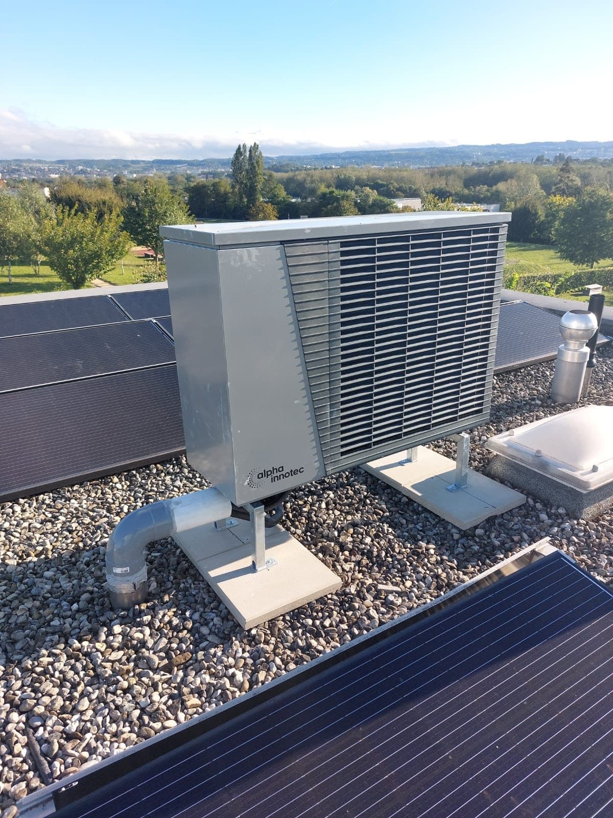alpha innotec heat pump on a flat roof with solar panels in Denges, Vaud