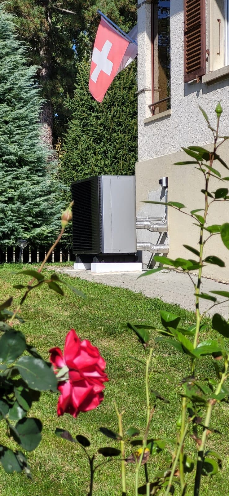 Air-to-water heat pump installed in the garden of a house in Domdidier, canton of Fribourg