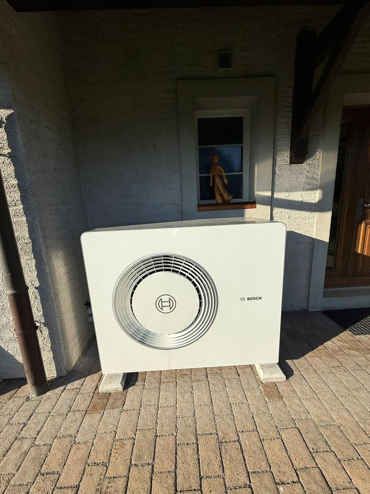 Bosch air-to-water heat pump installed under a shelter in Romanel-sur-Lausanne, Vaud